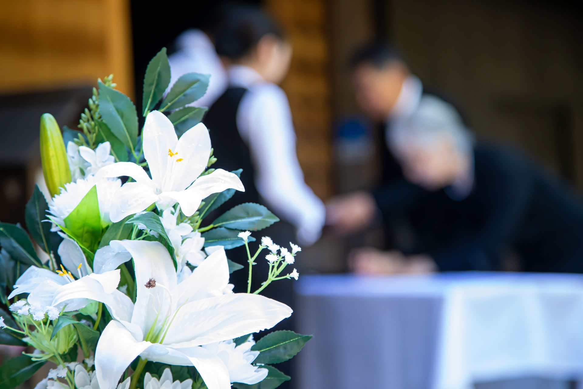 Bouquet de fleurs blanches avec en arrière plan des hommes préparent une cérémonie