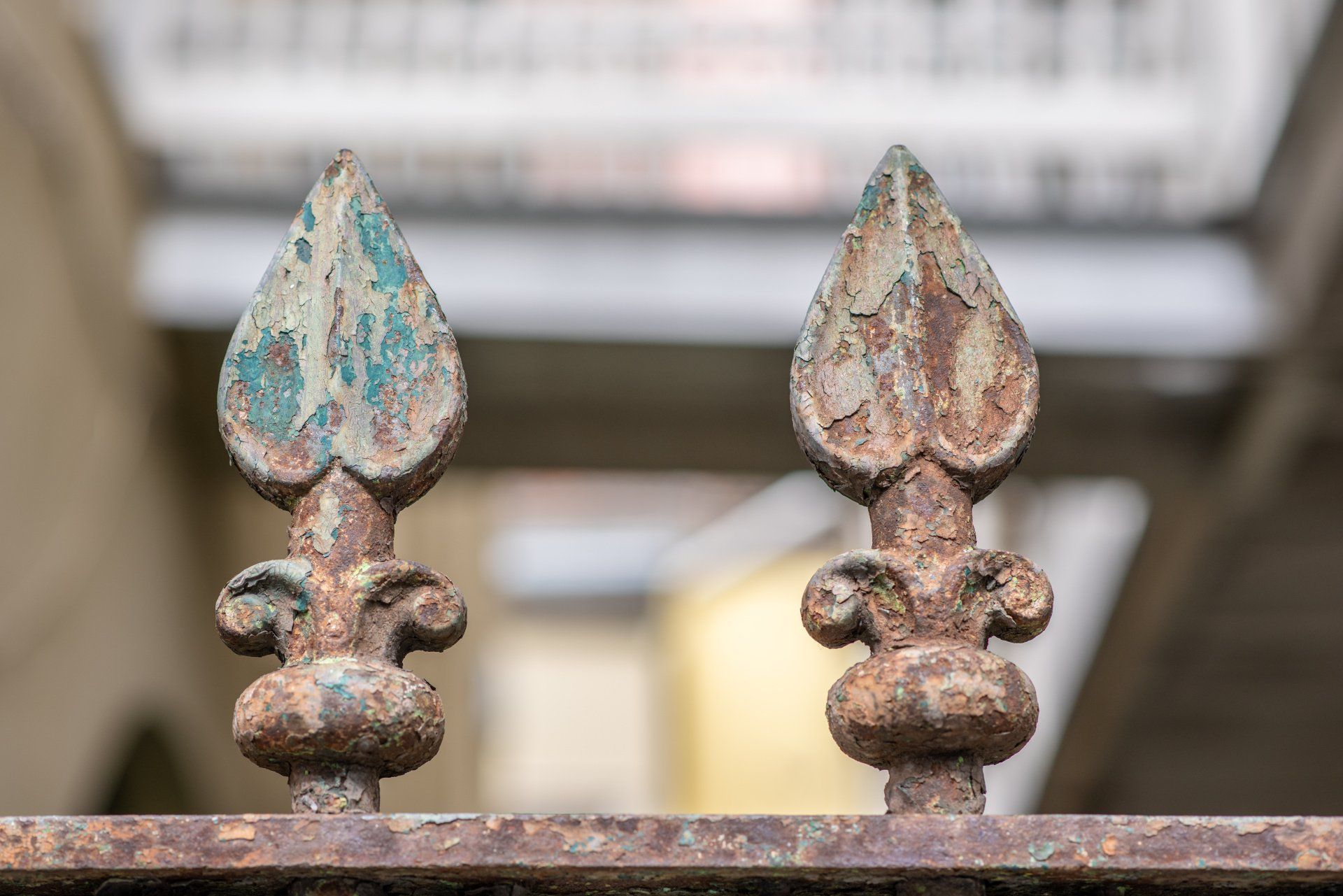 Deux poteaux de clôture en métal rouillé et orné, à la patine turquoise et brune.