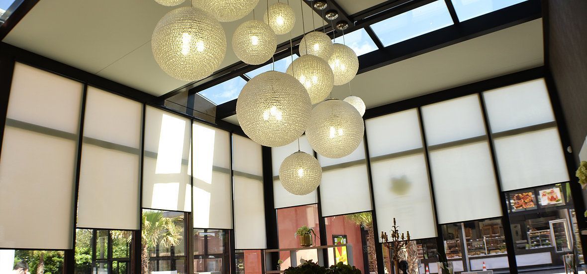 Des abat-jour blancs habillent les grandes fenêtres d'un espace intérieur ouvert.