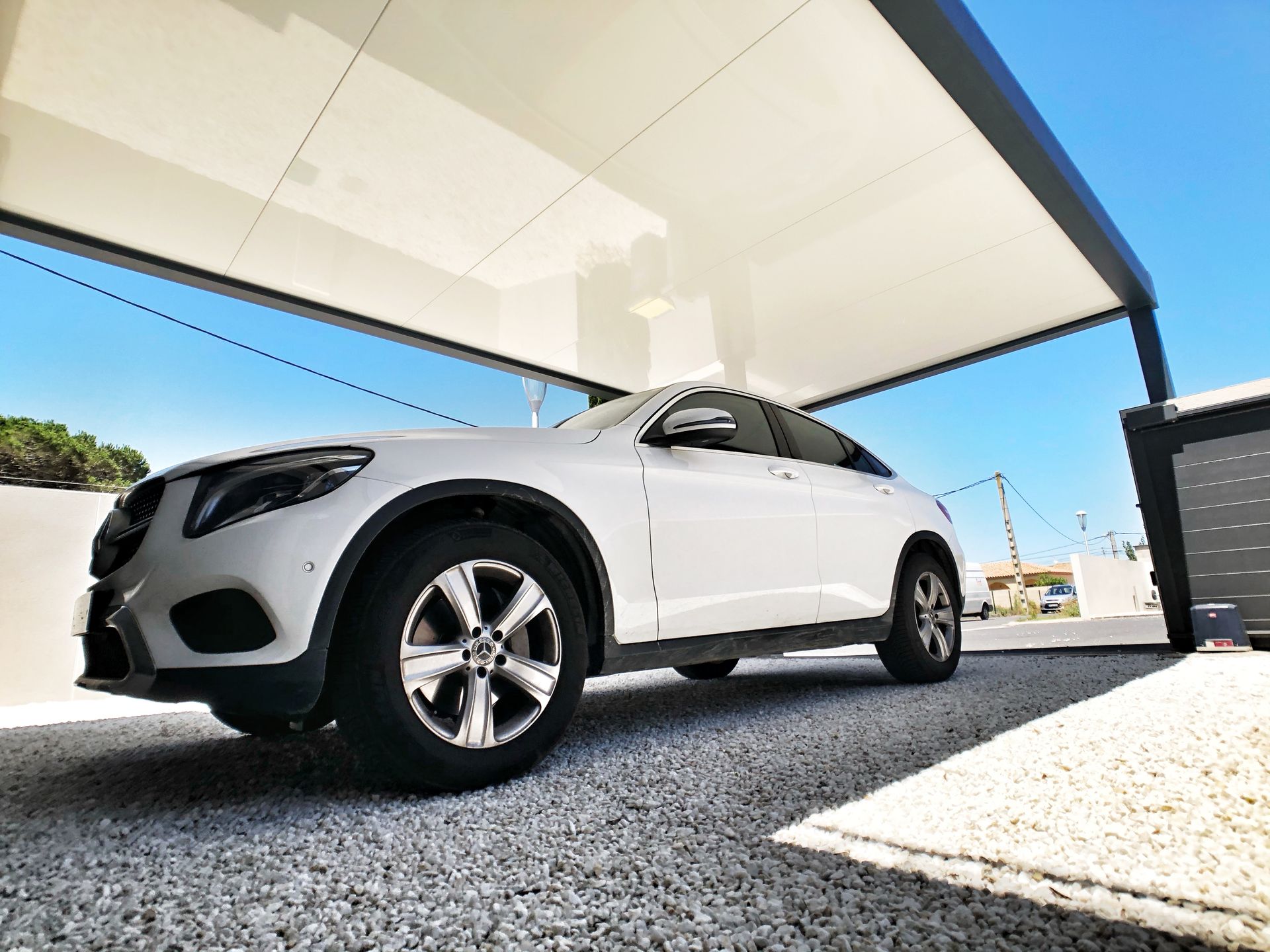 SUV blanc garé sous un auvent blanc par une journée ensoleillée.