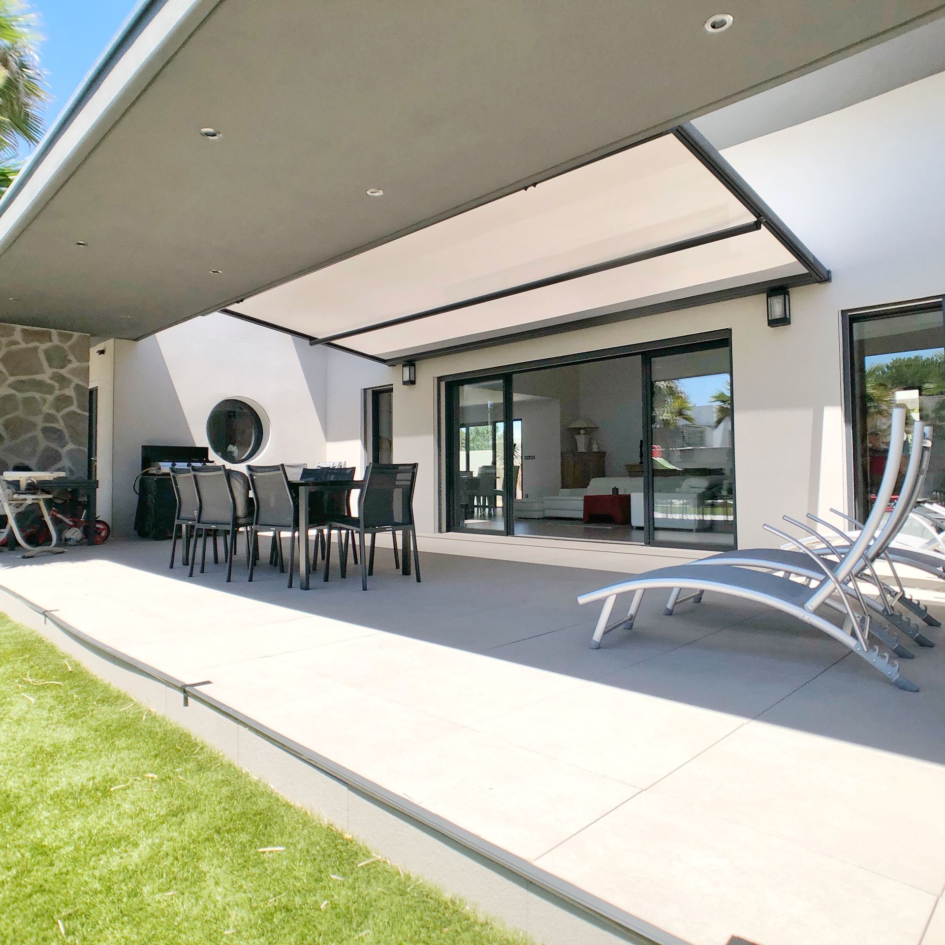 Patio avec ensemble de salle à manger, chaises longues et auvent rétractable.