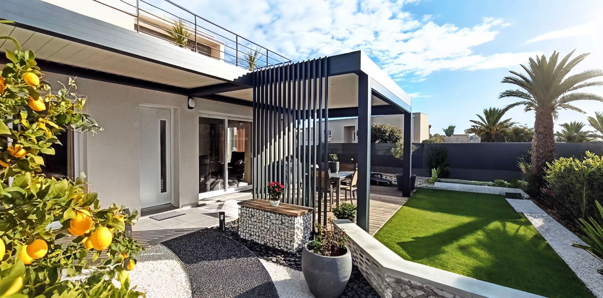 Extérieur d'une maison moderne avec une pergola, un jardin et un citronnier.