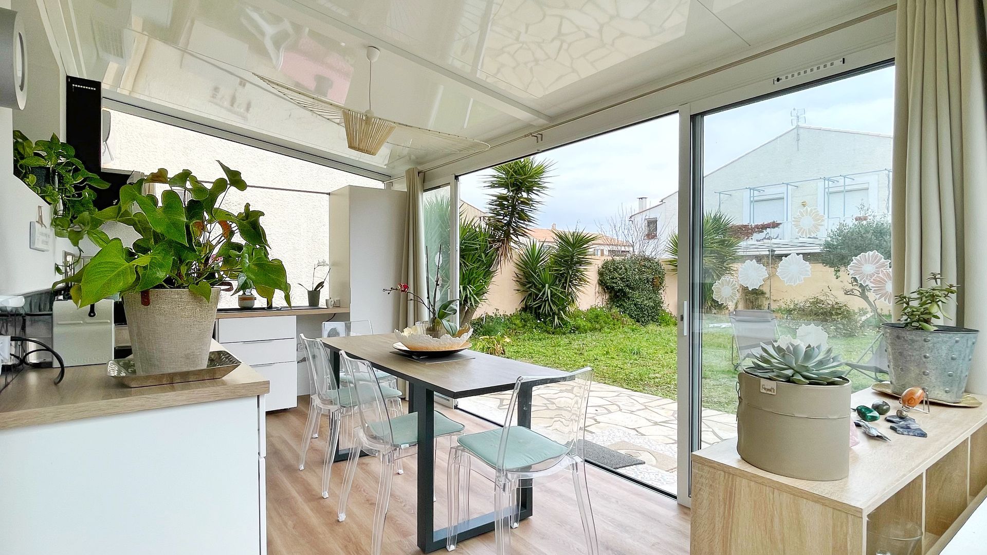 Cuisine véranda avec table à manger et vue sur une cour arrière.