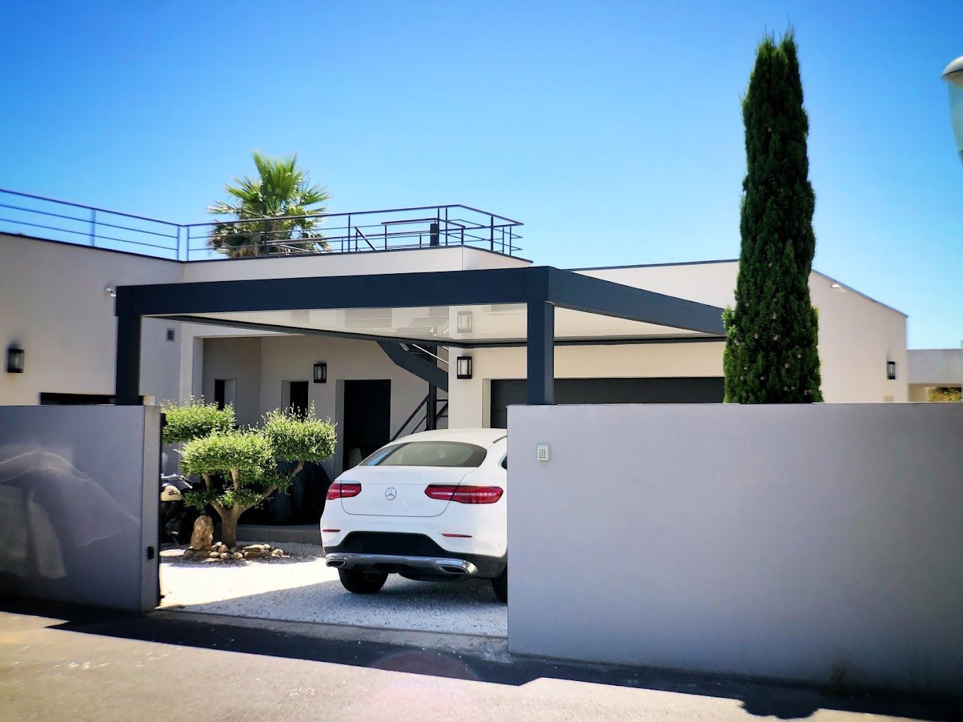 Véranda grise et voiture blanche garée