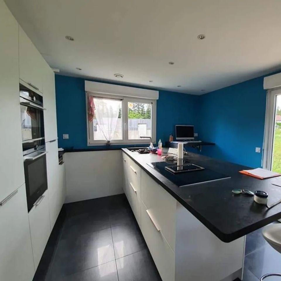 Une cuisine avec des murs bleus et des comptoirs noirs