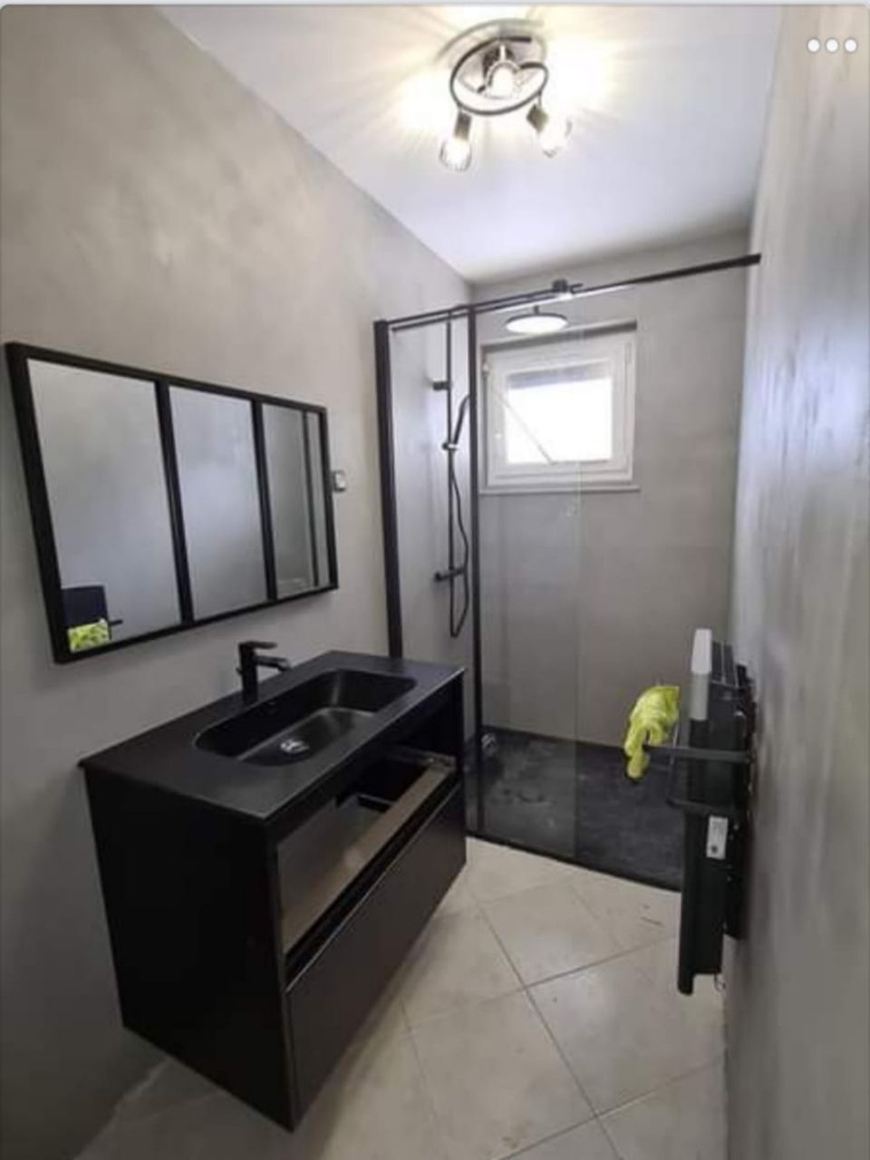 Une salle de bain avec lavabo, miroir et douche.