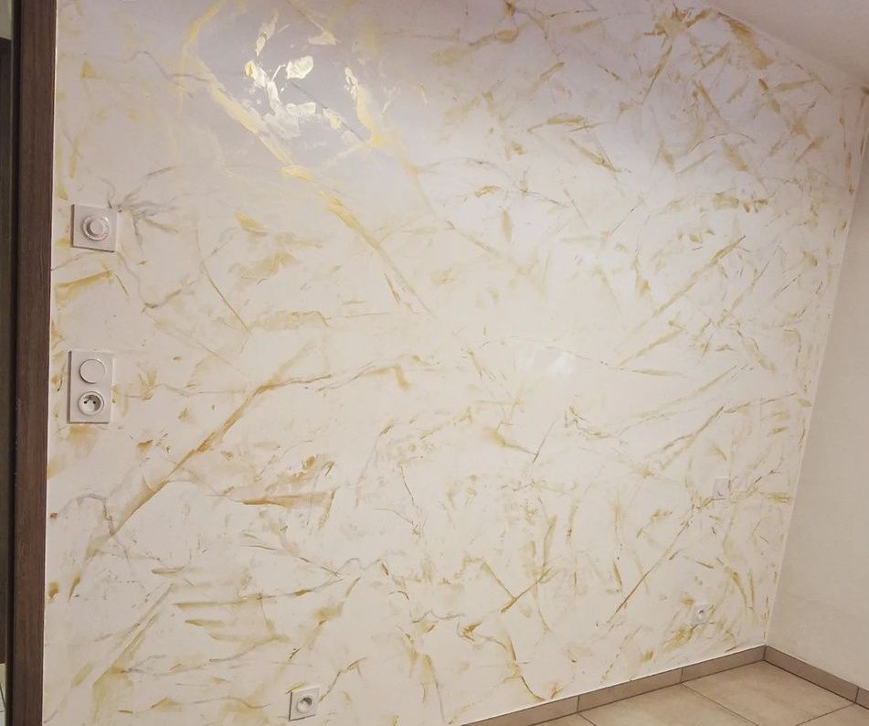 Une pièce avec un mur blanc effet marbre doré.