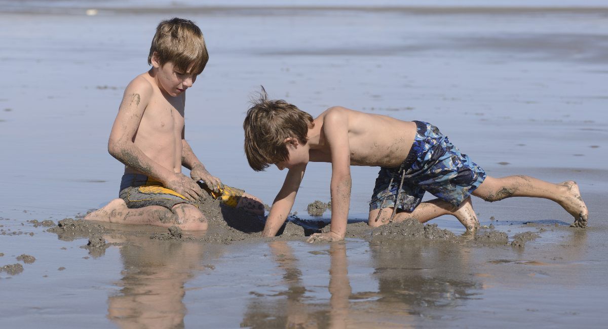 Two kids clamming in sand at the beach in Gearhart, Oregon