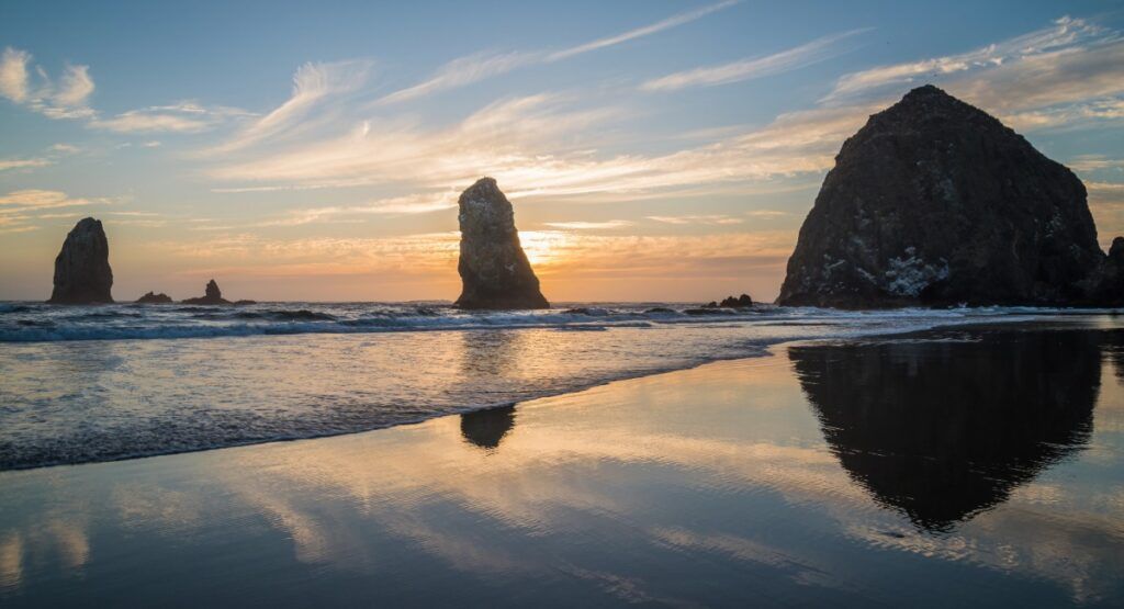 A beautiful evening sunset behind Haystack Rock on the Oregon Coast during winter Christmas vacation in Gearhart with dramatic sea stacks