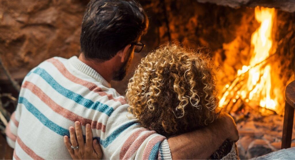 Couple relaxing by fireplace inside a cozy Gearhart vacation rental