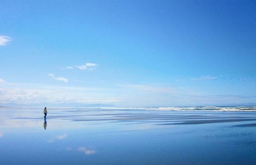 person walking along the wet sand at Seaside beach