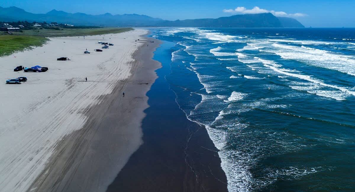 Aerial view of a beach and waves crashing against it in Gearhart