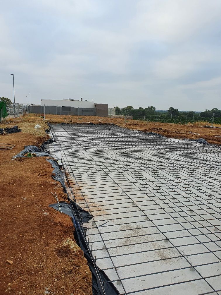 Se está construyendo una gran losa de hormigón en un campo de tierra.