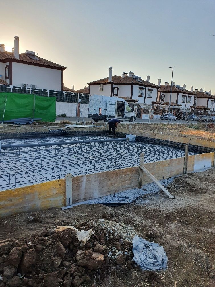 Un hombre está trabajando en una obra en construcción frente a una hilera de casas.