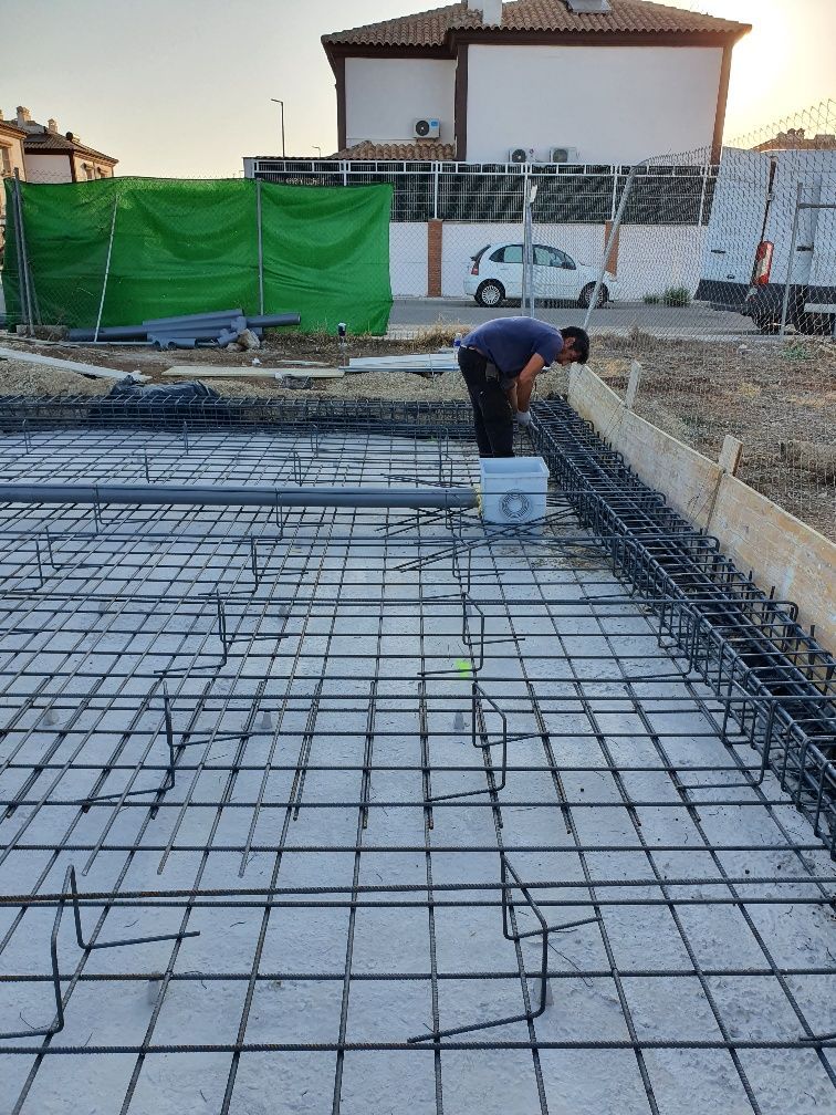 Un hombre está trabajando en un piso de concreto con un balde.