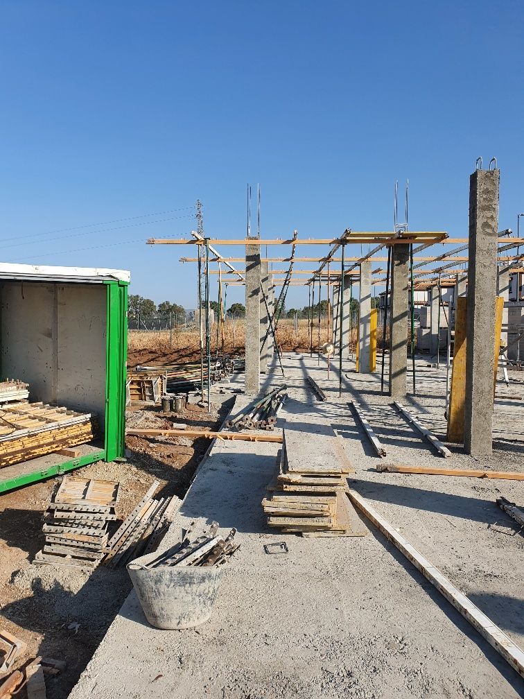 Una obra en construcción con un contenedor verde en primer plano.
