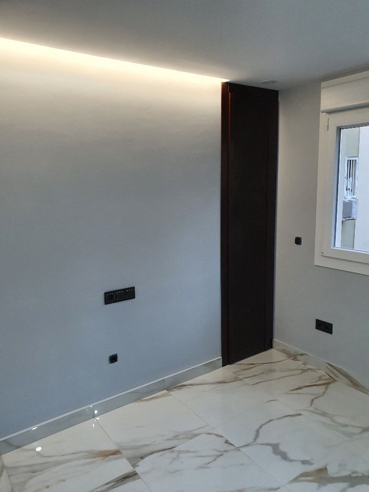 Una habitación con suelo de mármol, paredes blancas y una ventana.