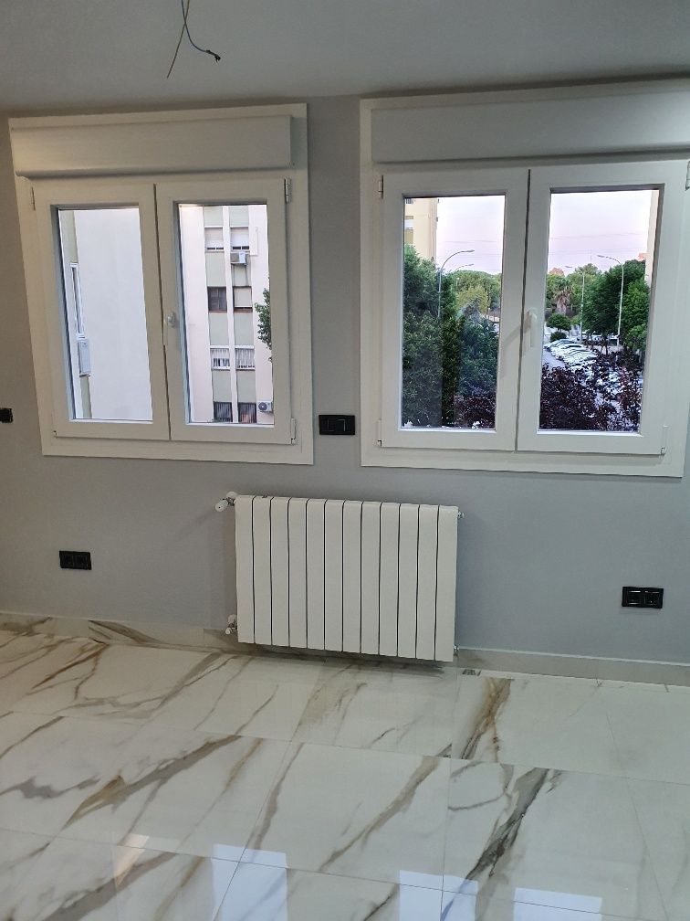 Una habitación vacía con dos ventanas y un radiador.