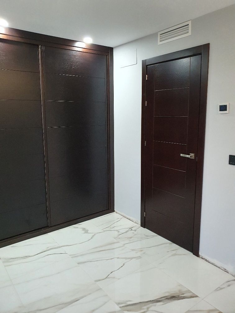 Hay una puerta en el medio de una habitación con piso de mármol.