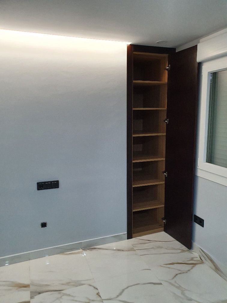 Un armario con una puerta abierta y estantes en una habitación.