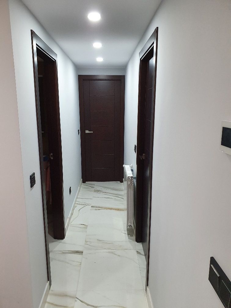 Un pasillo con dos puertas y un radiador en el suelo.