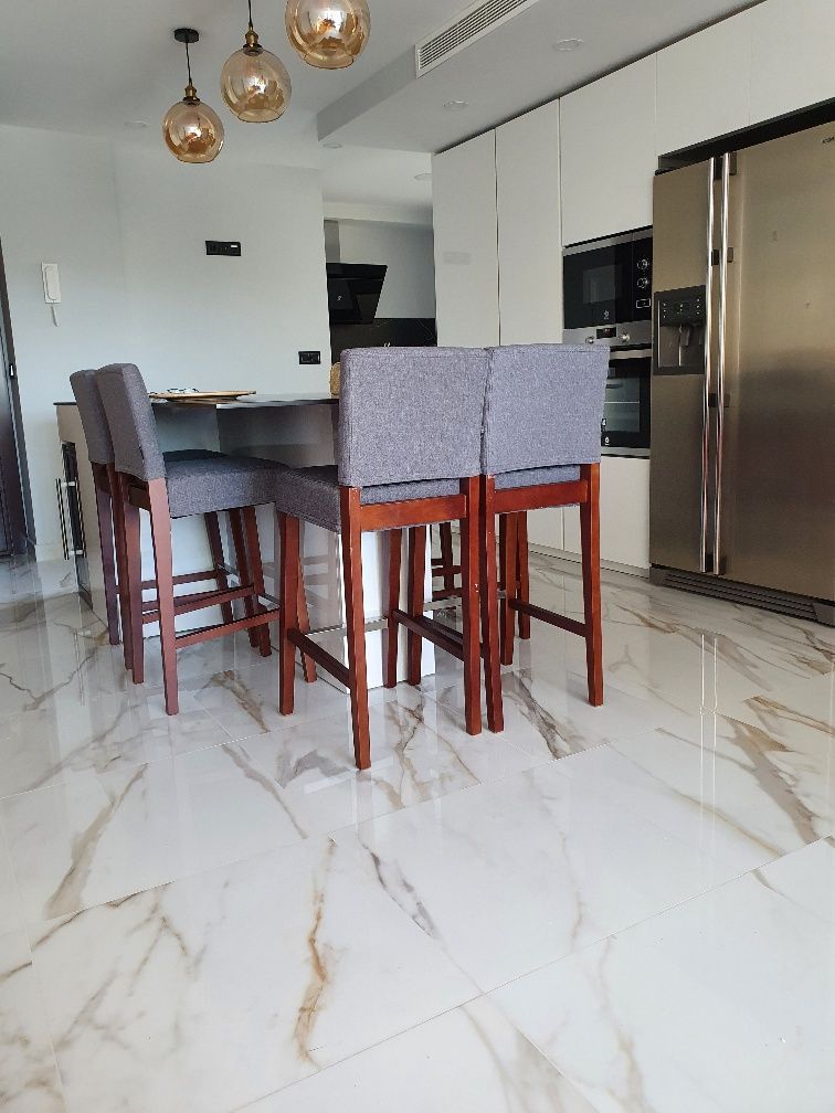 Una cocina con mesa y sillas y suelo de mármol.