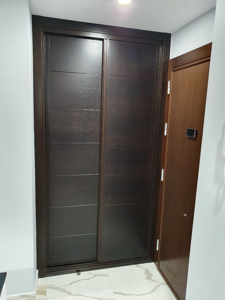 Un armario con puertas correderas en un pasillo al lado de una puerta.