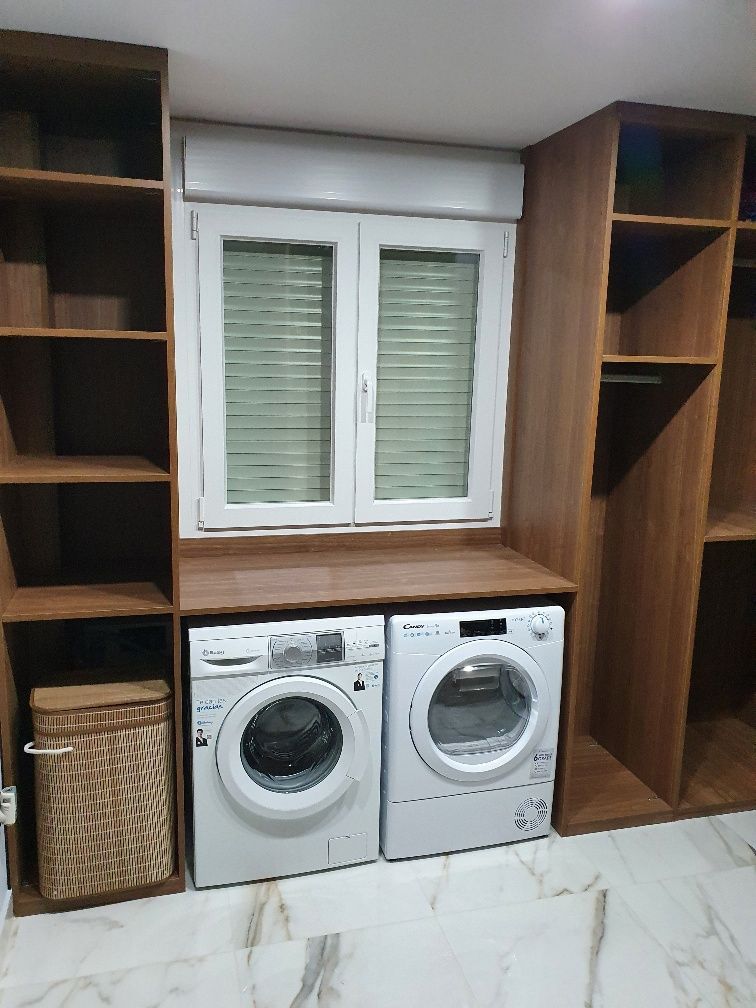 Una lavadora y una secadora están debajo de una ventana en un lavadero.