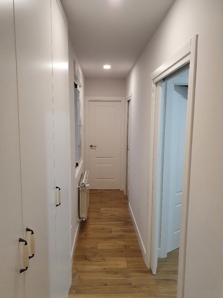 Un largo pasillo con paredes blancas y pisos de madera en una casa.