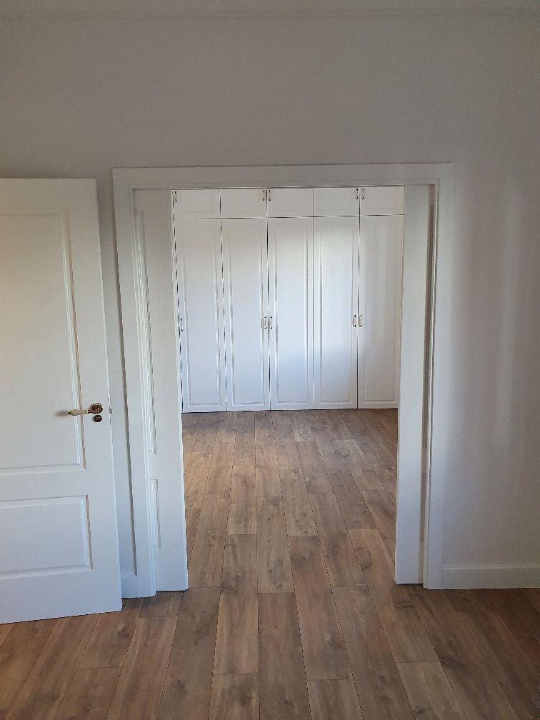 Una habitación con piso de madera y armarios blancos.