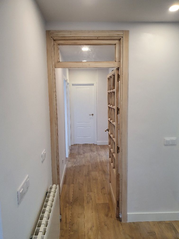 Un pasillo con pisos de madera y paredes blancas.