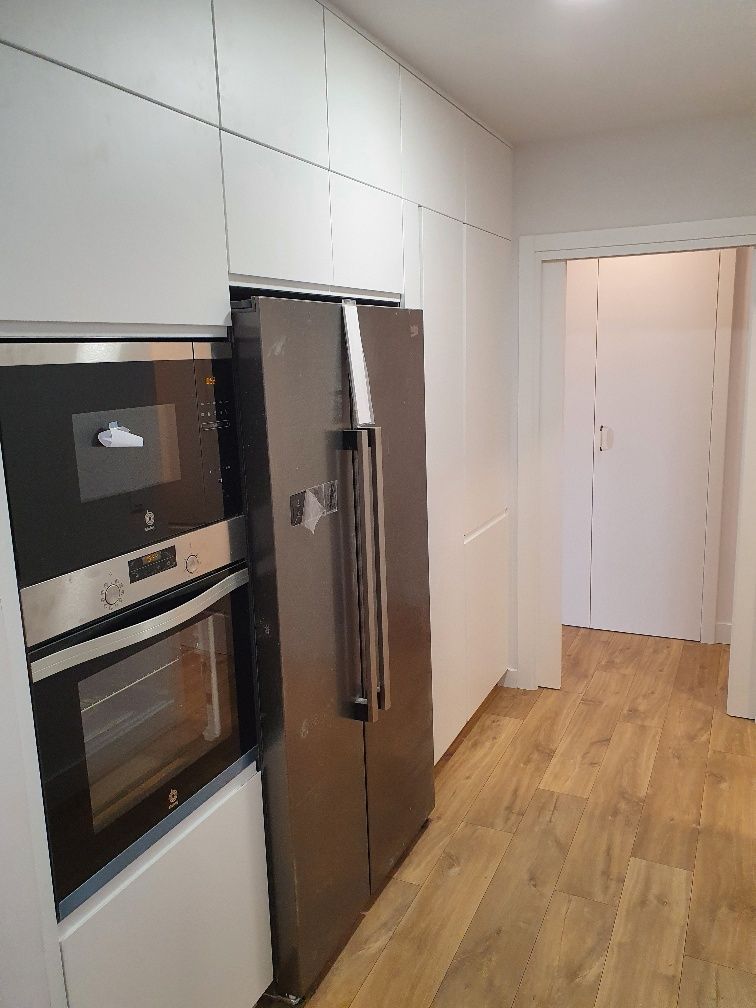 Una cocina con nevera, horno y microondas