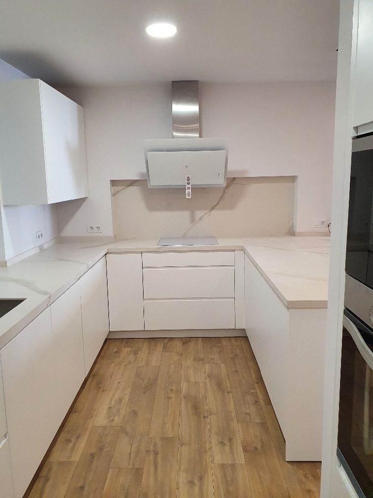 Una cocina con gabinetes blancos y pisos de madera.