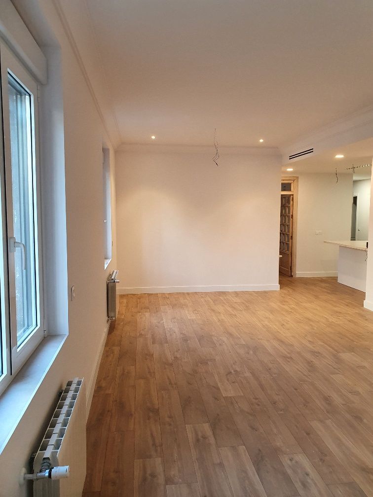 Una sala de estar vacía con pisos de madera y paredes blancas.