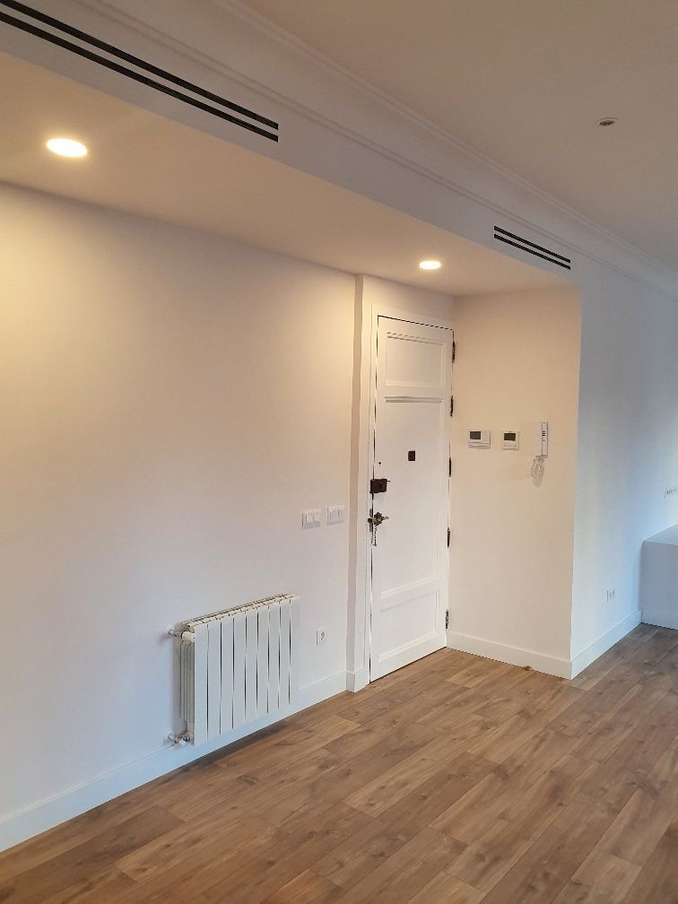 Una habitación vacía con un radiador y una puerta.