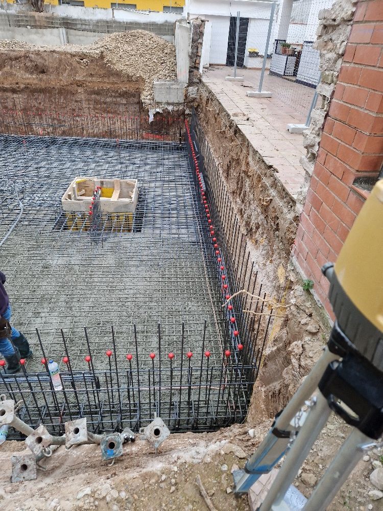 Un hombre está parado en un agujero en el suelo al lado de un edificio en construcción.
