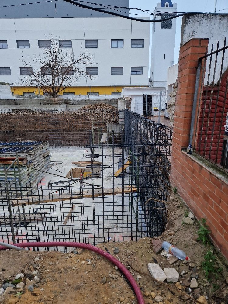 Un sitio de construcción con una pared de ladrillos y un edificio al fondo.