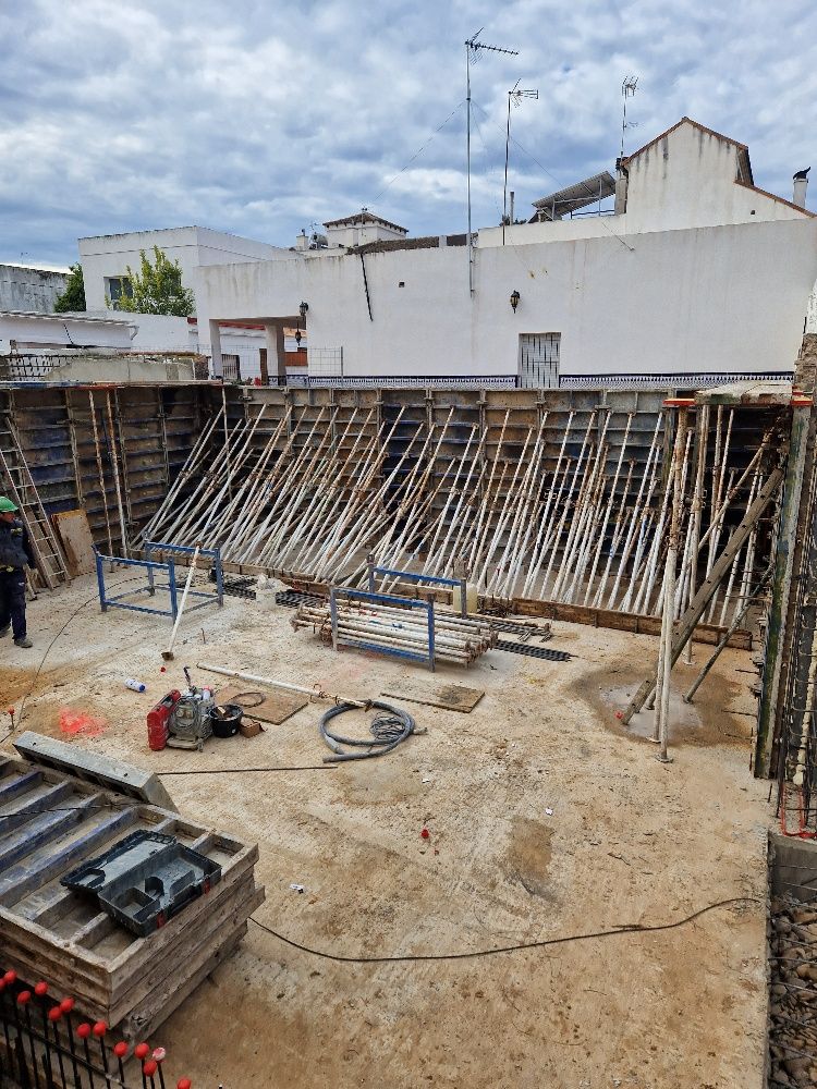 Una obra en construcción con muchos andamios de madera y un edificio al fondo.