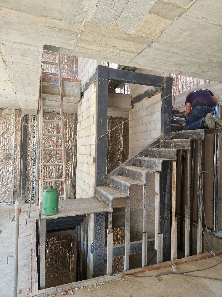 Un hombre está trabajando en un conjunto de escaleras en un edificio en construcción.