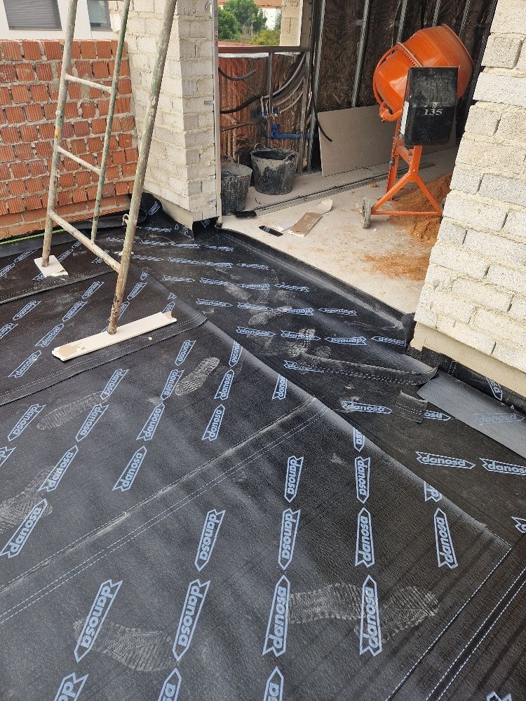 Una escalera está colocada encima de una lona negra delante de un edificio de ladrillos.