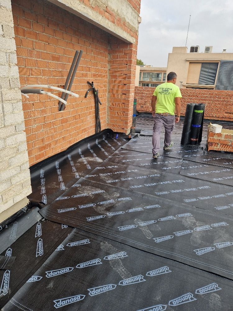 Un hombre con una camisa verde está parado en un tejado.