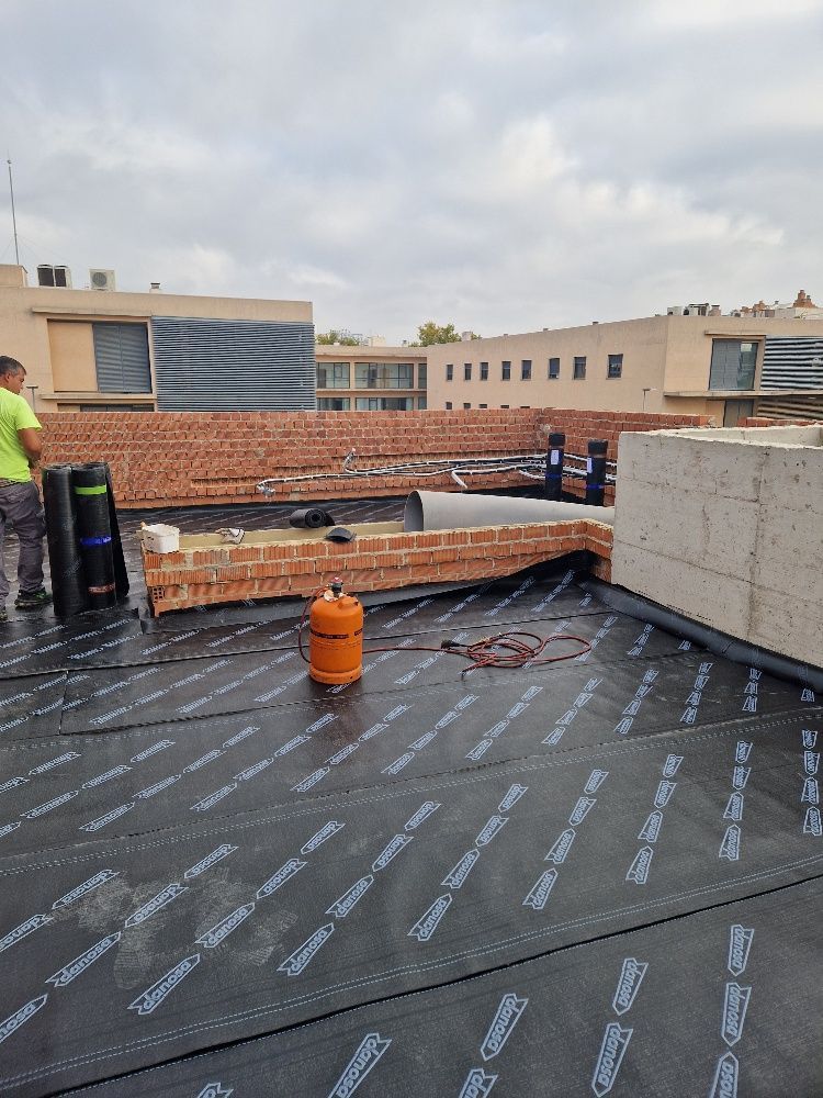 Un hombre está trabajando en el tejado de un edificio.