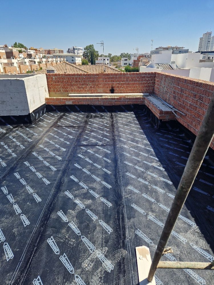 Se está impermeabilizando el techo de un edificio con una membrana negra.