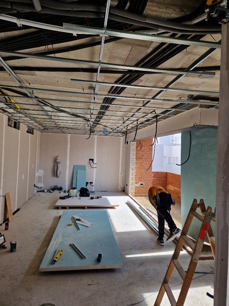 Un hombre está trabajando en el techo de una habitación con una escalera.
