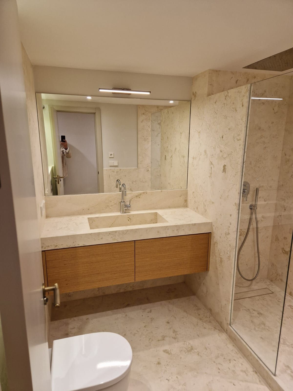 Un baño con inodoro, lavabo, espejo y ducha.