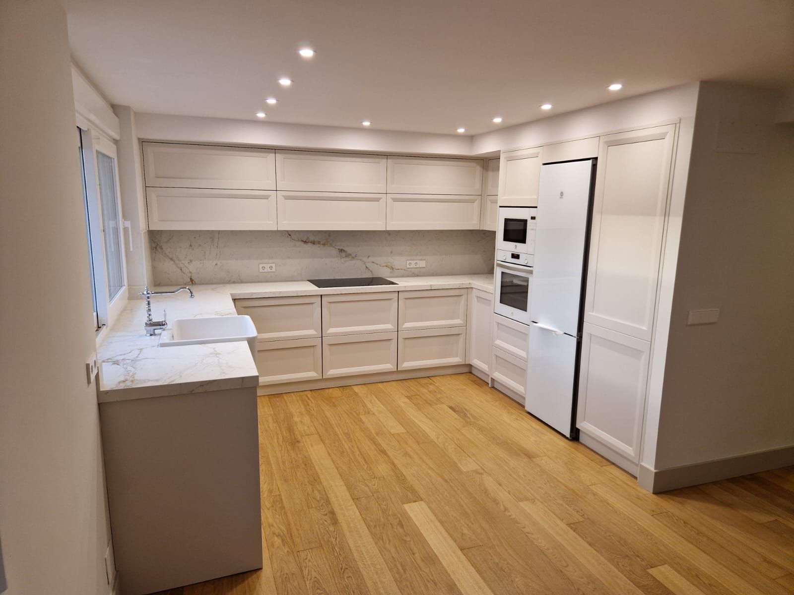 Una cocina con gabinetes blancos y pisos de madera.