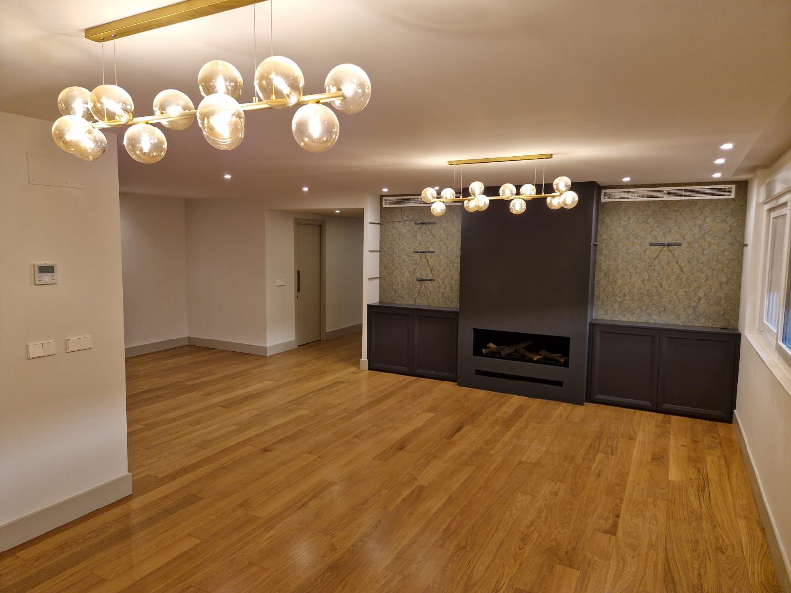 Una sala de estar vacía con pisos de madera y chimenea.