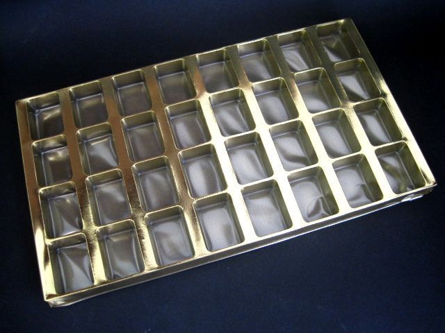 Una bandeja dorada con cuadrados transparentes en su interior.