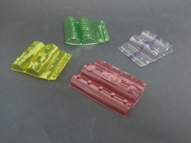 Cuatro contenedores de plástico de diferentes colores están sobre una mesa.