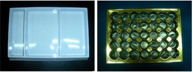 Una bandeja de plástico blanca y una bandeja dorada con chocolates dentro.